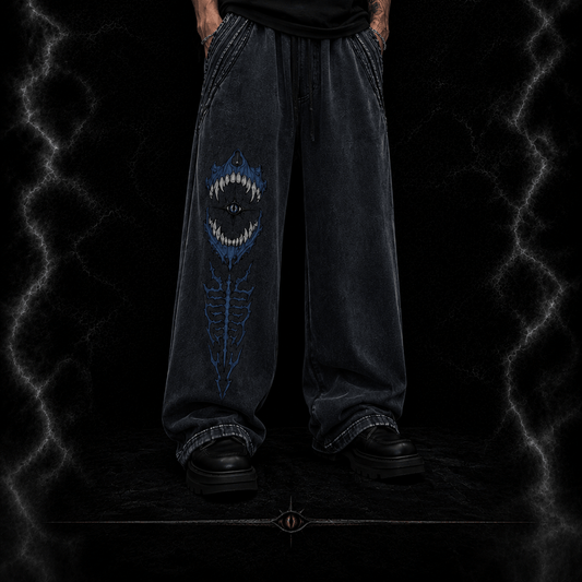 Person wearing dark jeans with a unique design on a dark background