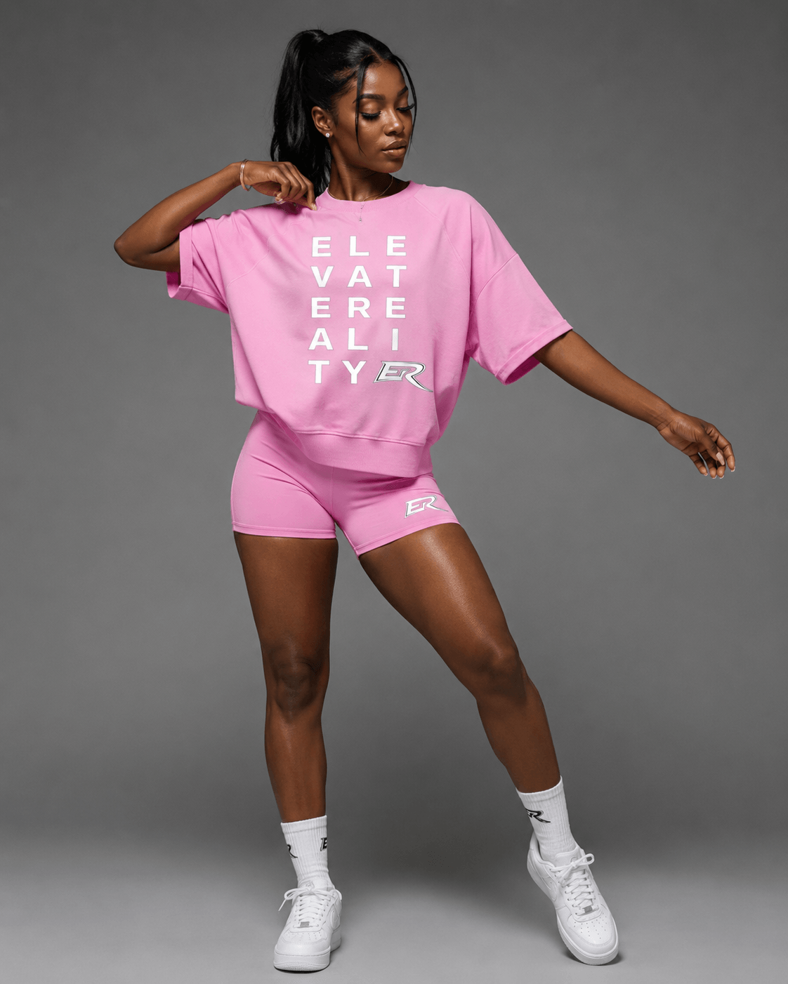 Woman wearing matching pink Short Sleeve Pump Cover and athletic shorts set front view