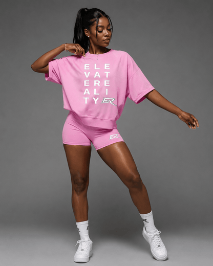Woman wearing matching pink Short Sleeve Pump Cover and athletic shorts set front view